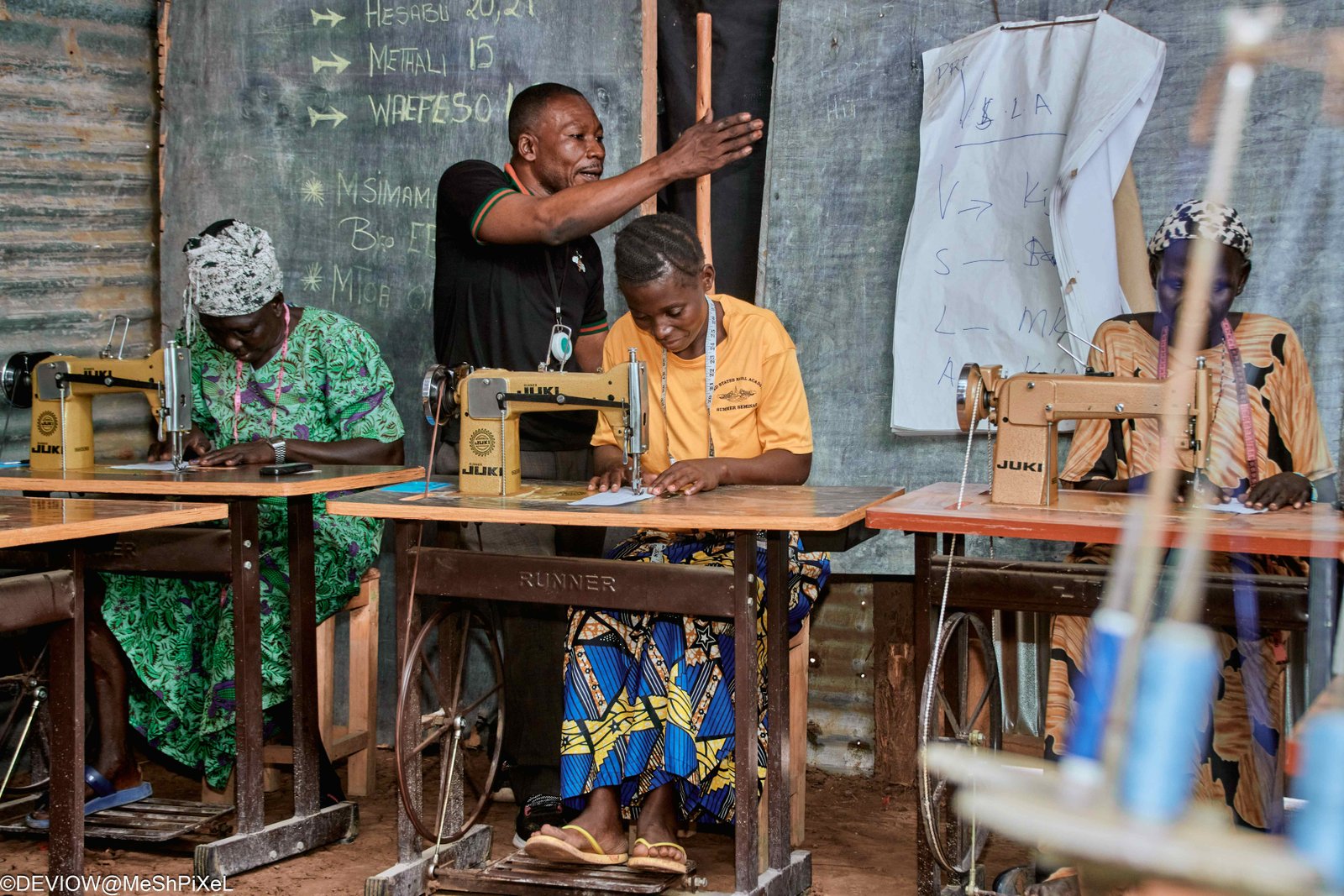 Tailoring mentor teaching women at sewing machines